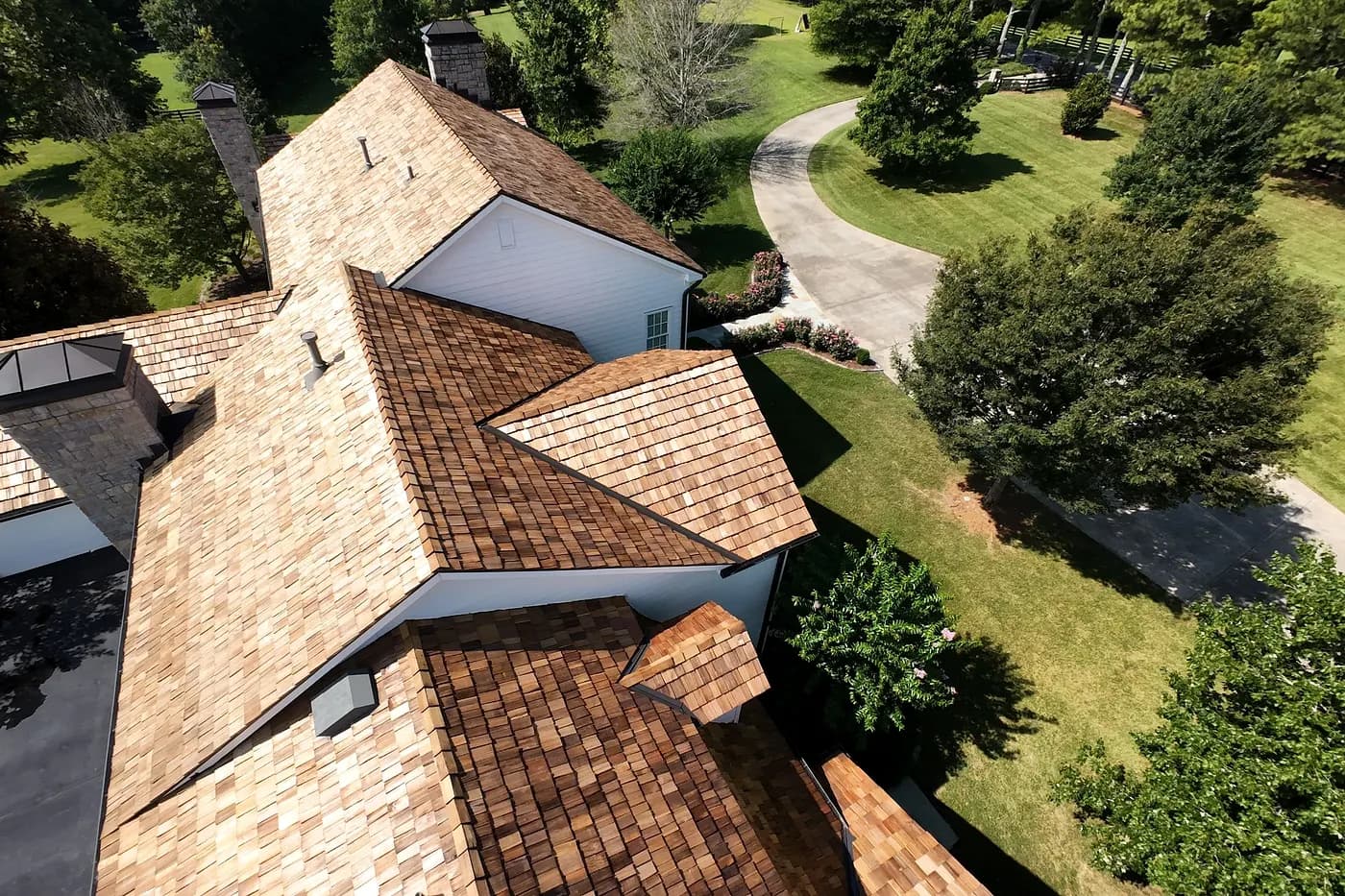 A finished cedar shake roof from above, courses running into the valleys, the tone varying shake to shake.