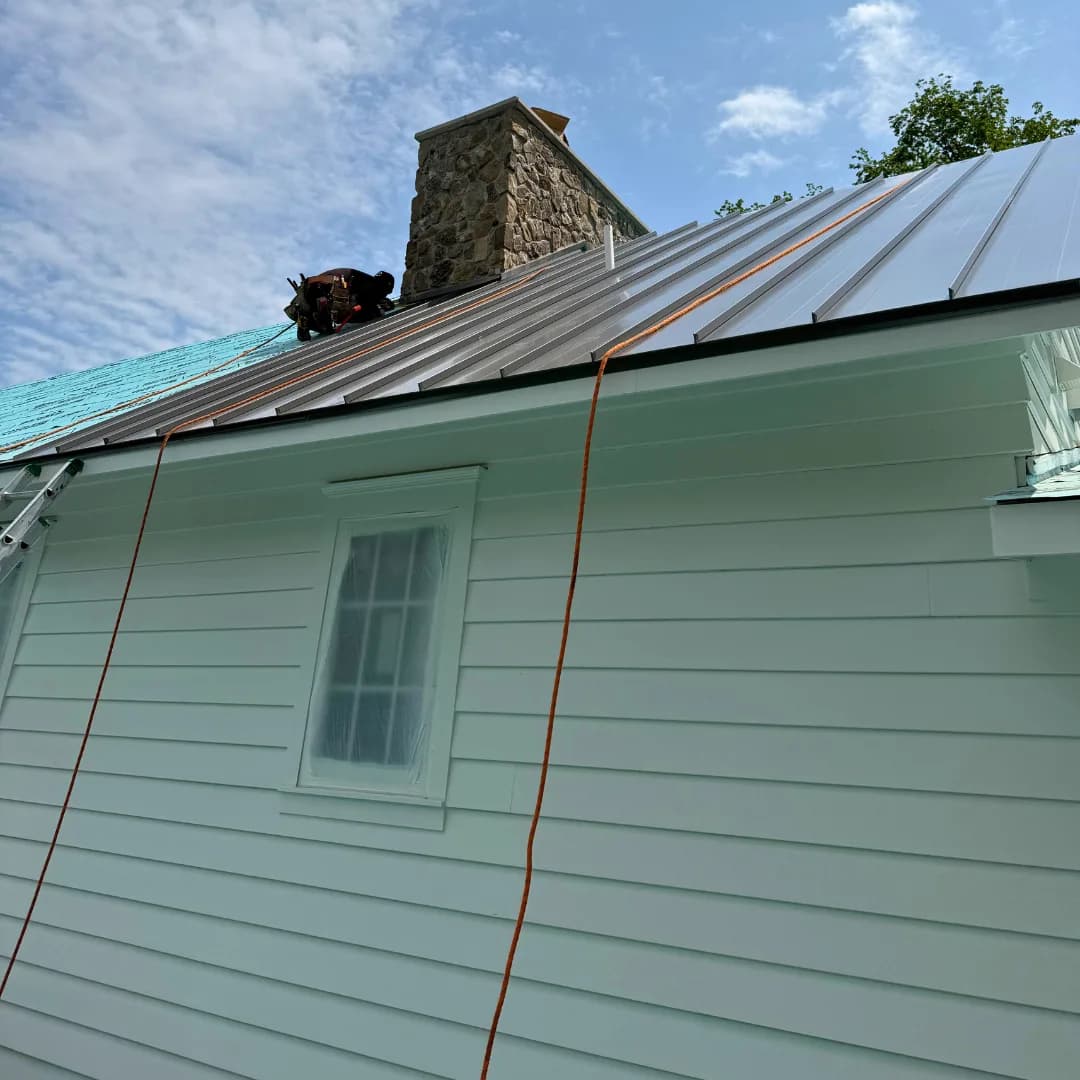 Close view of standing-seam panels running to a stone chimney.