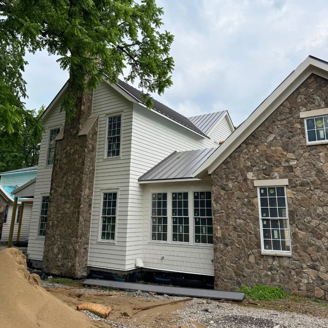 Metal roof meeting stone and lap siding on a house still under construction.