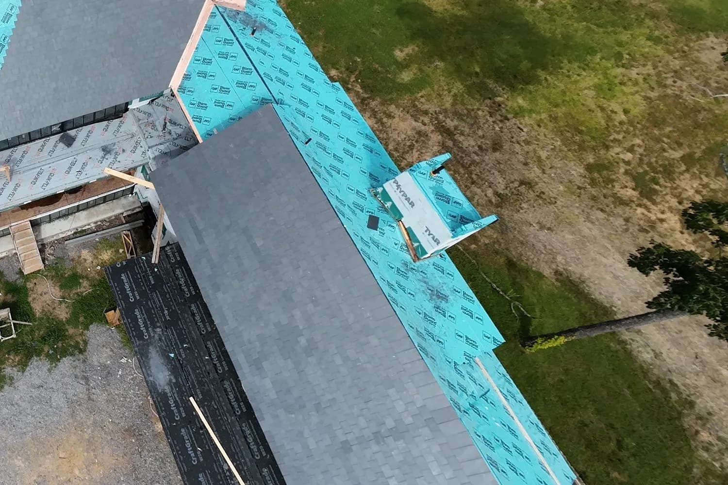 A finished plane of architectural shingle on an AEM job, the laminated courses running to the ridge beside the leak barrier they were laid over.