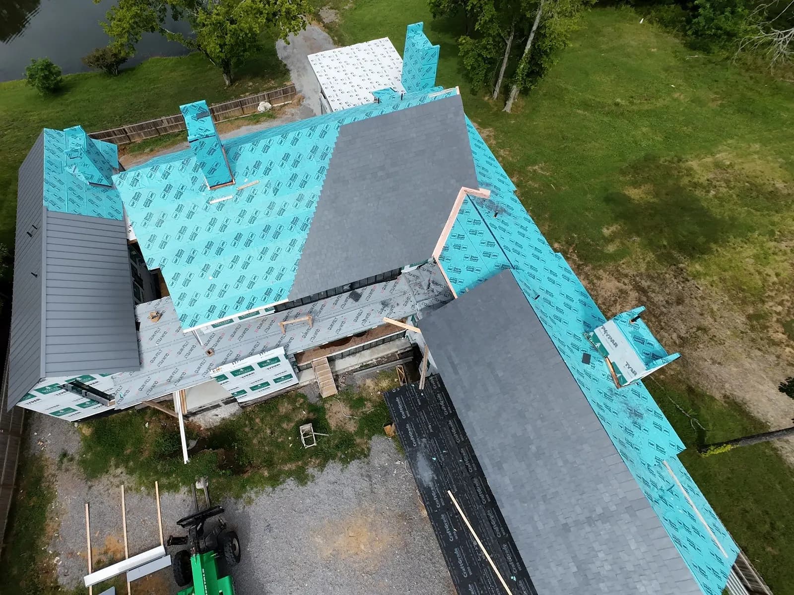 An AEM roof seen from directly above mid-replacement: underlayment over bare deck on one half, architectural shingle courses advancing across the other.